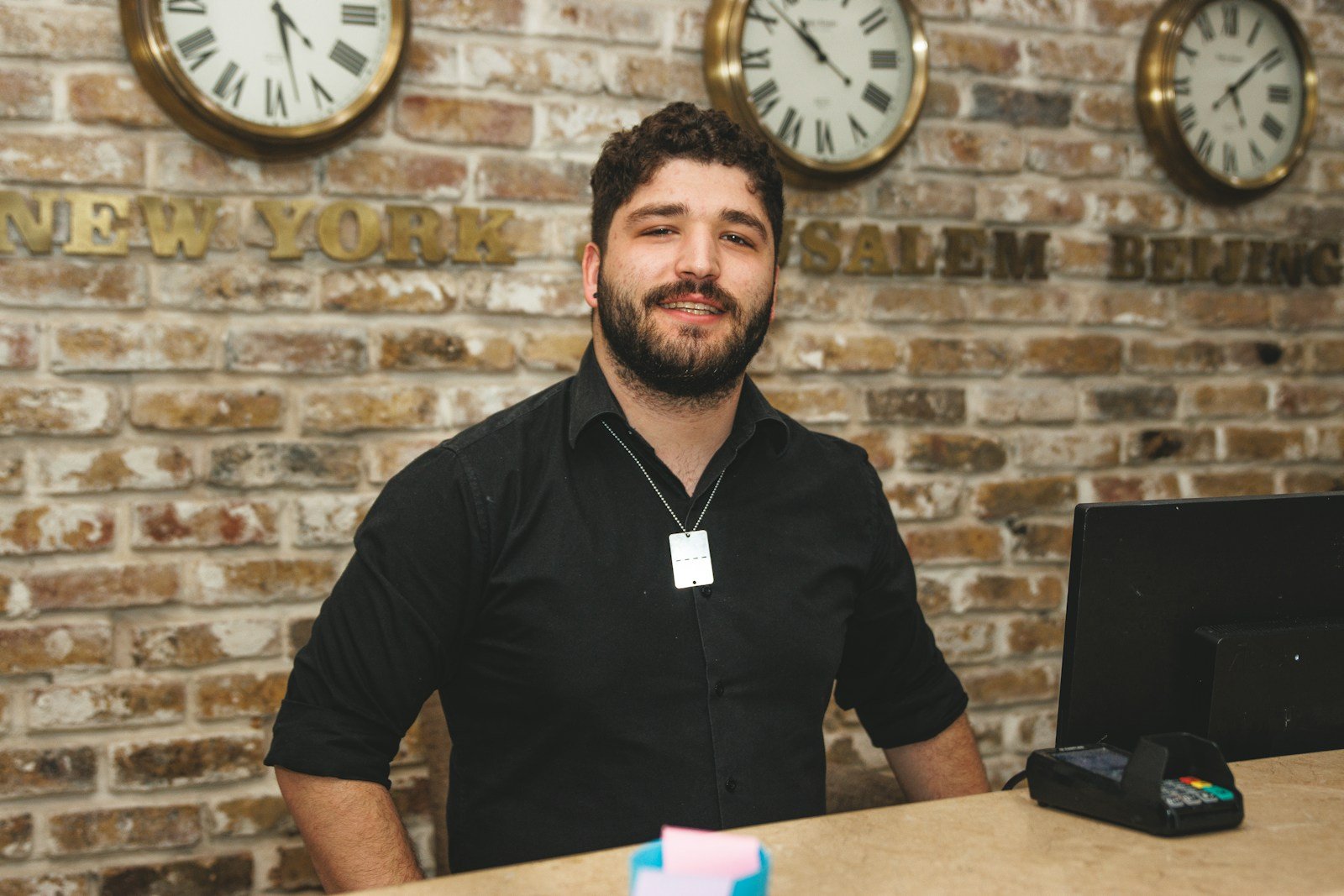 a man sitting at a desk in front of a brick wall