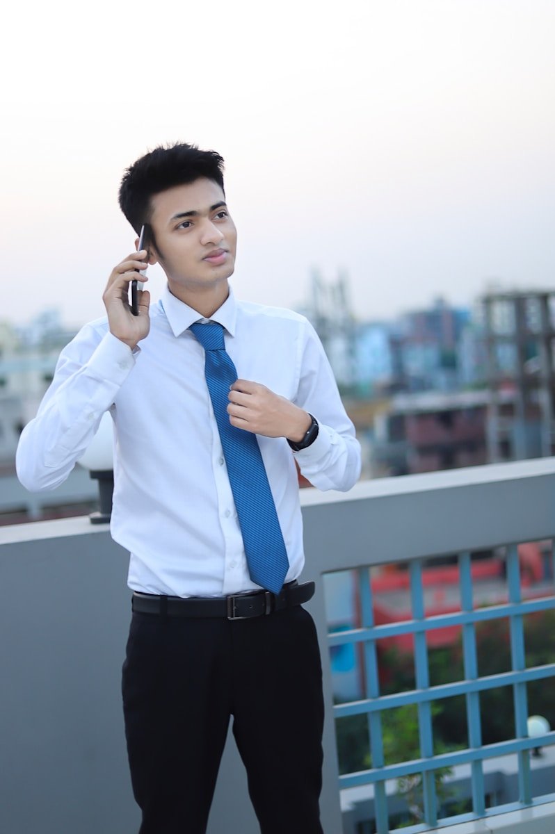a man in a dress shirt and tie talking on a cell phone
